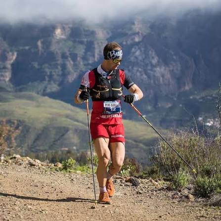 Pere Aurell on a mountain trail with poles and Merrell bib number 12